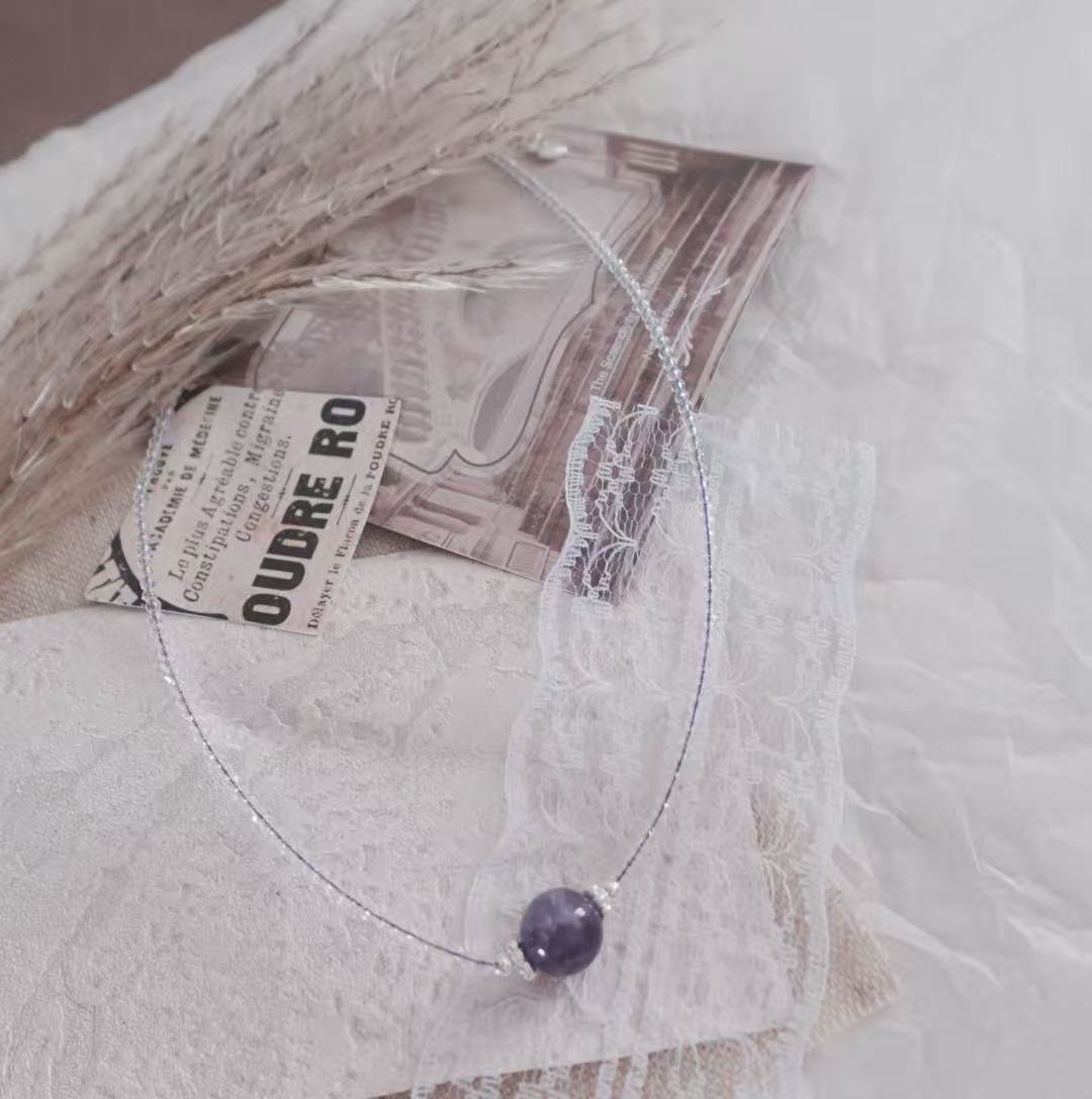 Delicate Amethyst Beaded Necklace on a textured background, showcasing its elegant design