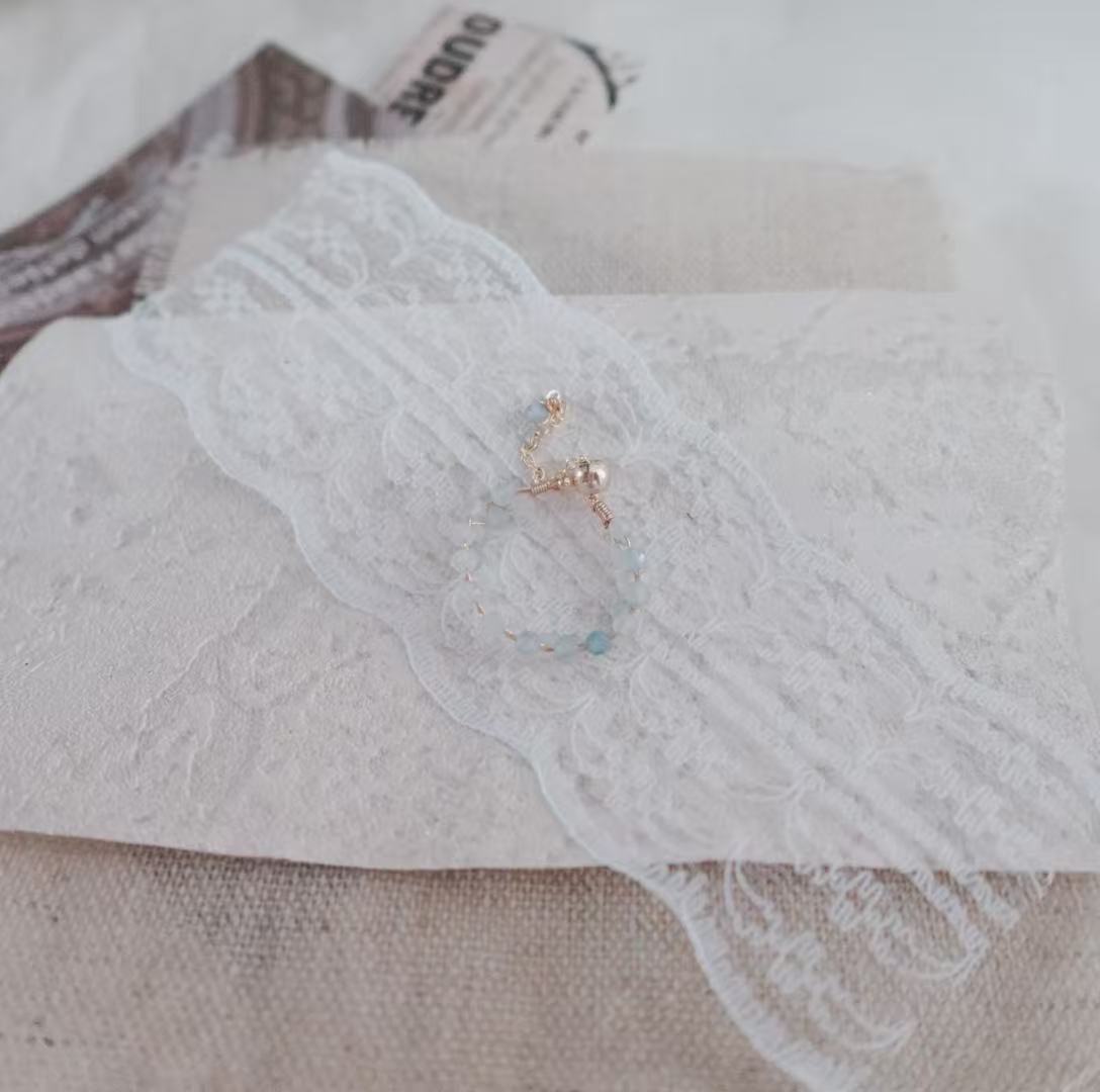Aquamarine Faceted Bead Ring displayed on delicate lace with textured background for elegant accessory appeal