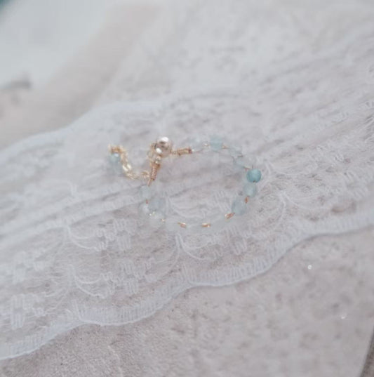 Delicate Aquamarine Faceted Bead Ring with Gold Accents on a Lace Background