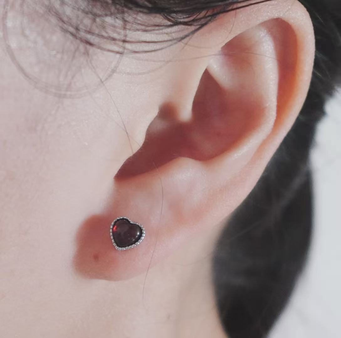 Natural Garnet Heart Stud Earrings set in silver, showcased on a model's ear
