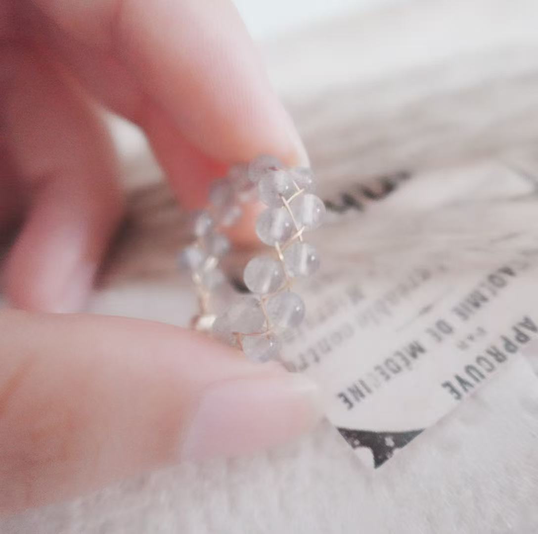 Close-up of a Labradorite Bead Ring held by a hand, showcasing its unique crystal design