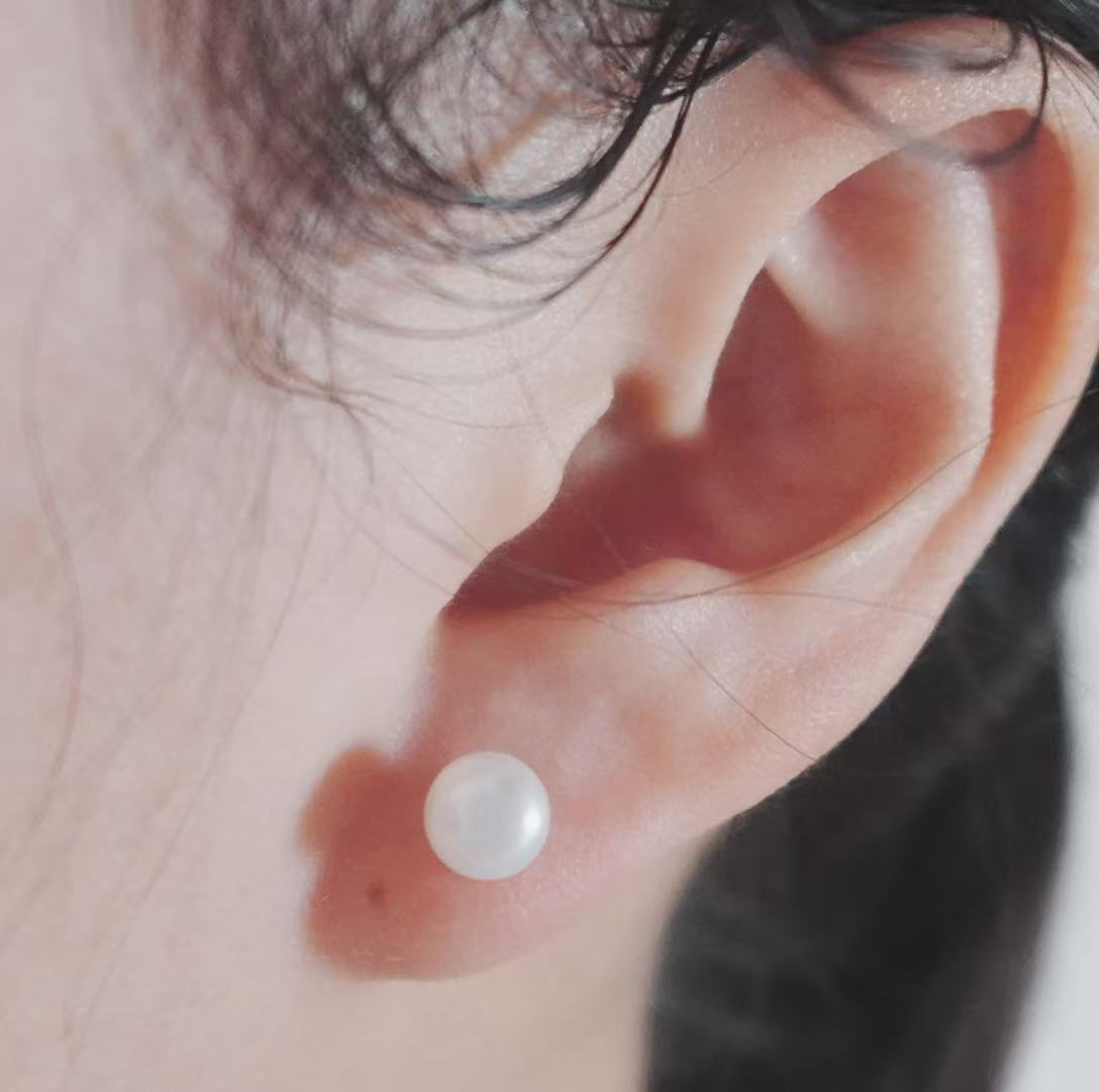 Natural Freshwater Pearl Oval Stud Earrings worn on a model's ear for elegant style