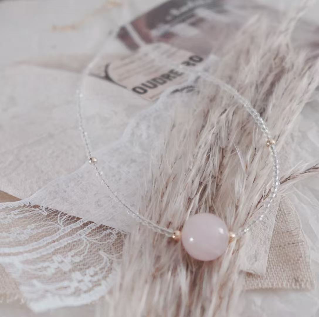 Elegant Rose Quartz Beaded Necklace with Clear Beads and Gold Accents on a Soft Background