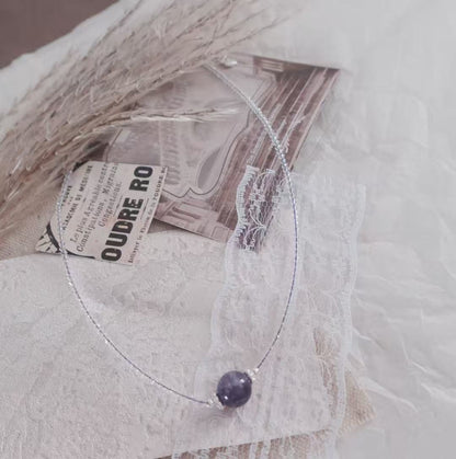 Delicate Amethyst Beaded Necklace on a textured background, showcasing its elegant design