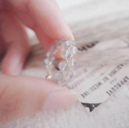 Close-up of a Labradorite Bead Ring held by a hand, showcasing its unique crystal design