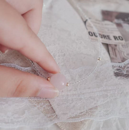 Hand showing a Rose Quartz Beaded Necklace on soft lace fabric for a delicate touch