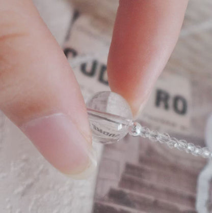 Close-up of a White Crystal Beaded Necklace showing a clear bead being held between fingers
