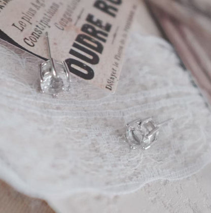 Elegant White Crystal Faceted Stud Earrings on a Lace Background with Vintage Postcard